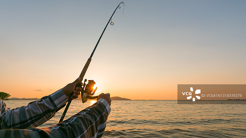 日出时分的钓鱼竿轮特写图片素材