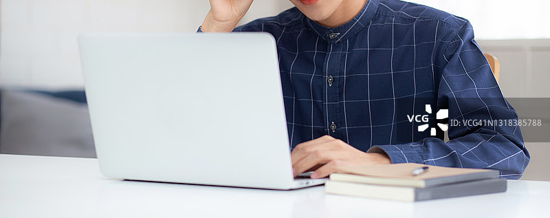 戴眼镜的年轻商人在家使用笔记本电脑工作，自由职业者居家办公图片素材