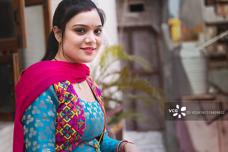 站在阳台上呼吸新鲜空气并看向镜头的印度年轻女子图片素材