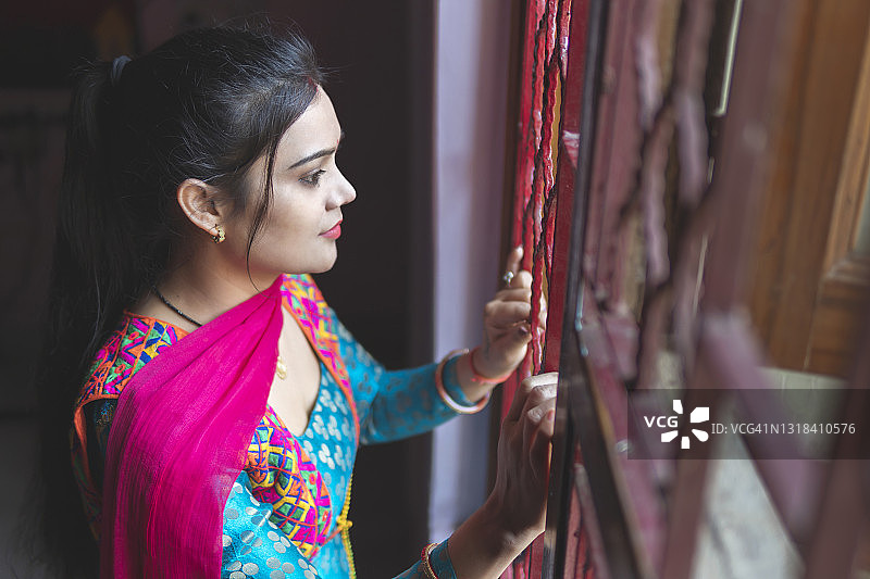 美丽的印度年轻女子站在房子窗户旁沉思图片素材