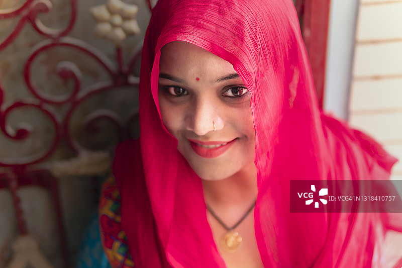 用粉色dupatt头巾遮住头部的印度年轻女子肖像图片素材
