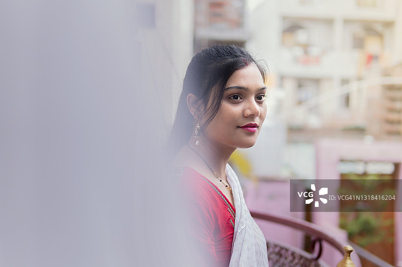 站在阳台上呼吸新鲜空气沉思的漂亮印度年轻女人图片素材