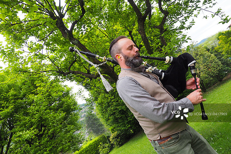 在花园里吹奏风笛的年轻男子图片素材