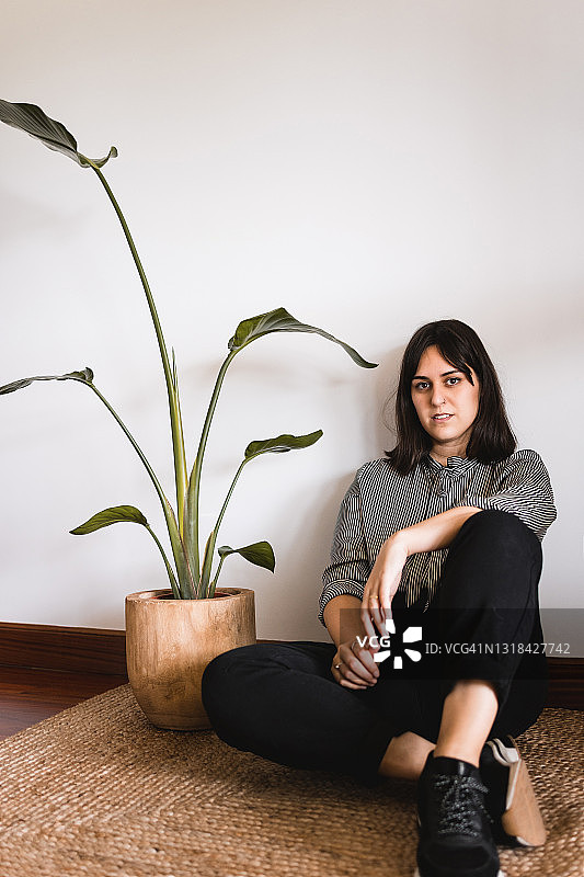 坐在黄麻地毯上，天堂鸟植物旁的白人中年妇女图片素材