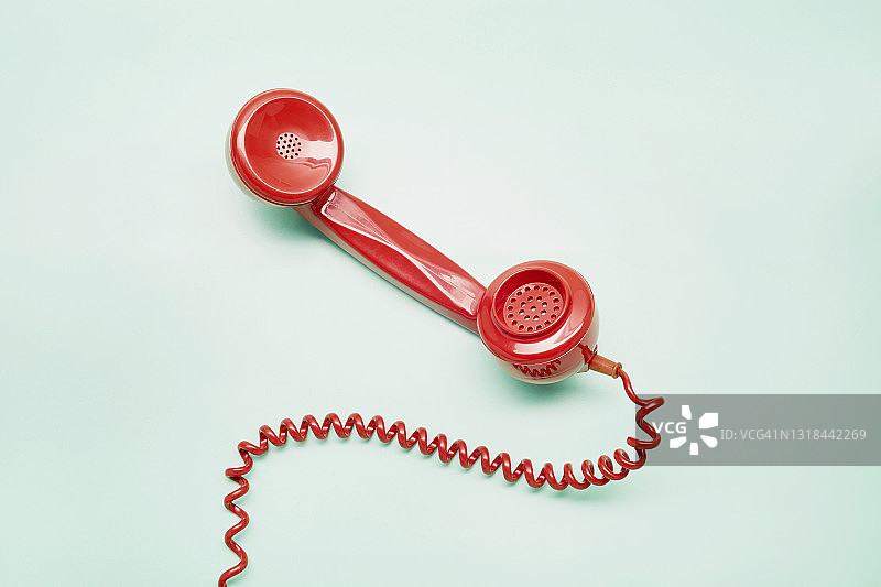 绿松石背景上的红色老式电话听筒图片素材