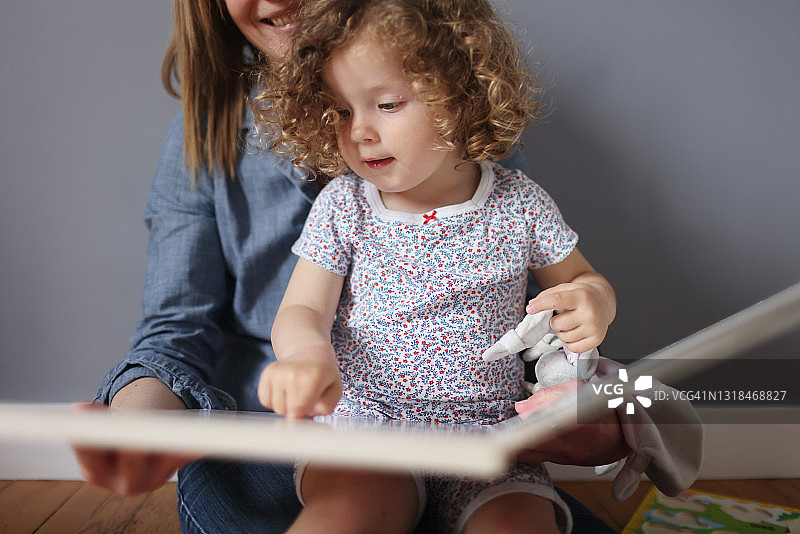 2岁女孩和妈妈在家一起读书图片素材