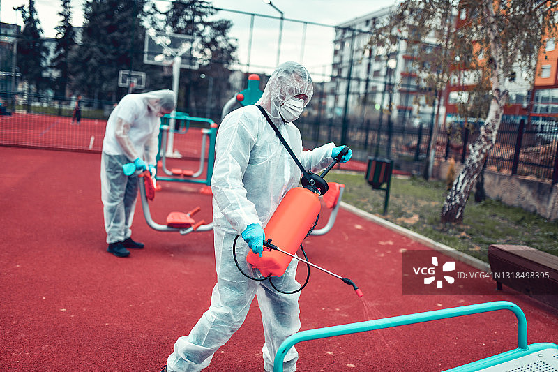 身穿防护服的医务人员对户外健身器材进行消毒图片素材
