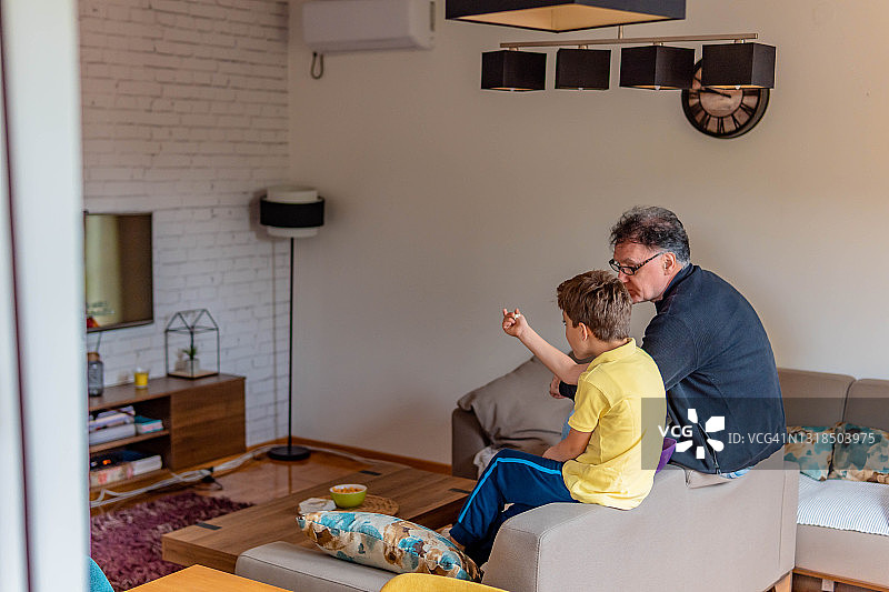 爷爷和孙子在客厅沙发上看电视图片素材