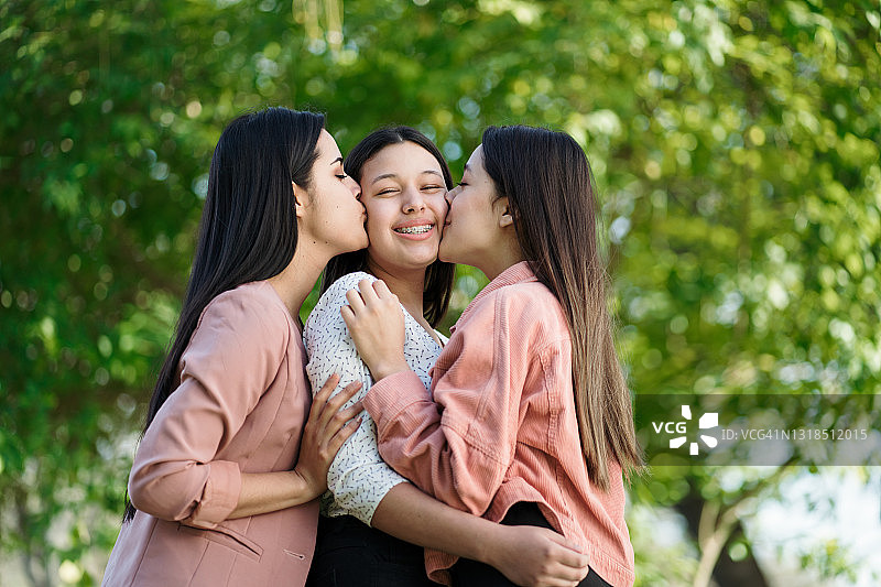 年轻姐妹亲吻彼此的脸颊，表达爱意图片素材