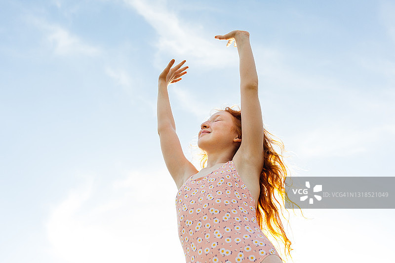 向天空伸出双手的红发女孩图片素材