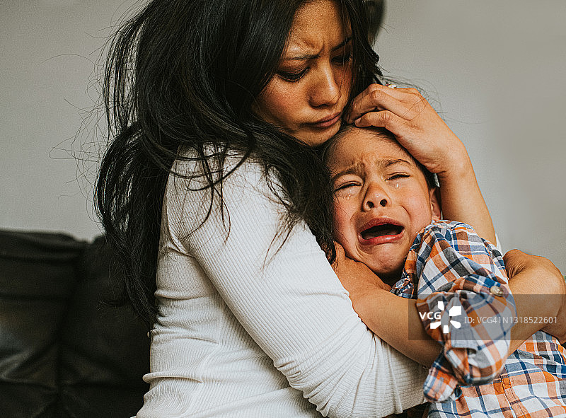 小男孩在母亲的怀里哭泣，母亲安慰着他图片素材