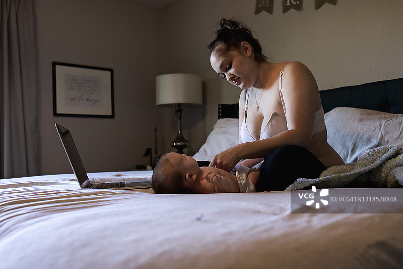 母亲在床上给儿子换布尿布图片素材