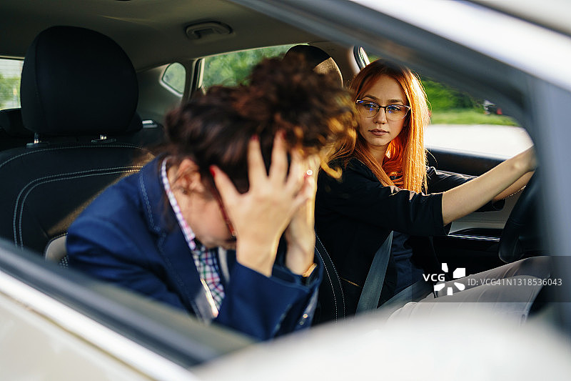 驾校或考试。美丽的年轻女人和她的教练一起学习如何开车。图片素材