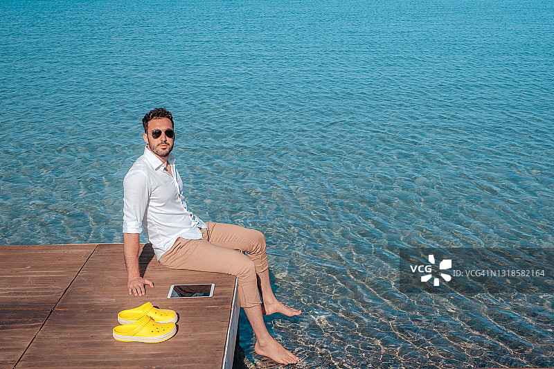 在海边用平板电脑看经济数据的年轻商人图片素材