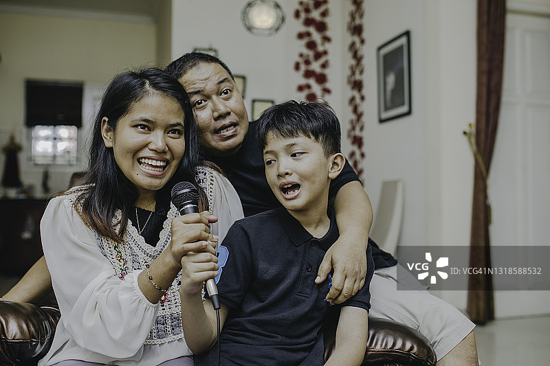 亚洲家庭在客厅里一起唱歌、欢笑和享受卡拉OK图片素材