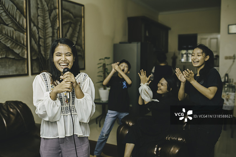 亚洲家庭在客厅里一起唱歌、欢笑和享受卡拉OK图片素材