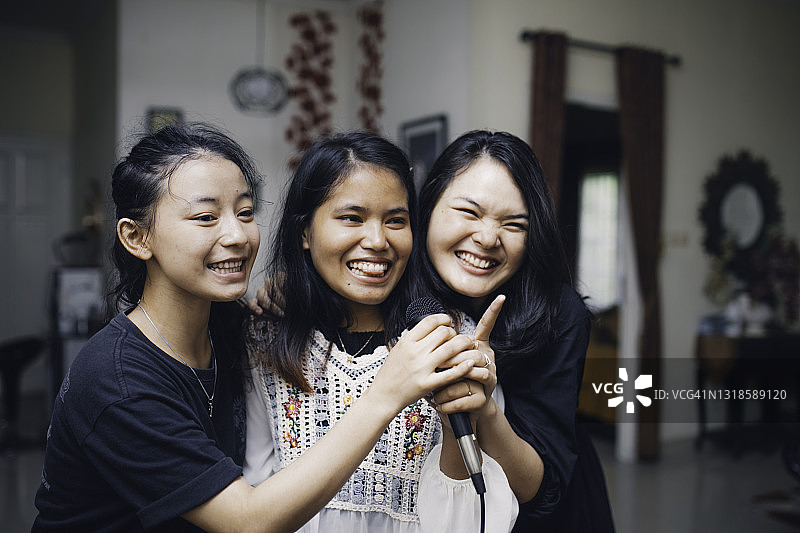 亚洲女性在客厅里唱歌、欢笑图片素材