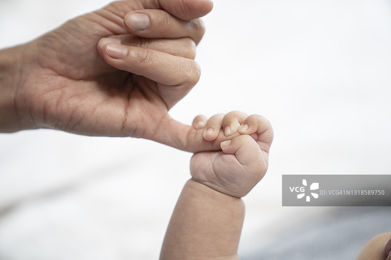 熟睡的婴儿紧握着母亲的手指图片素材