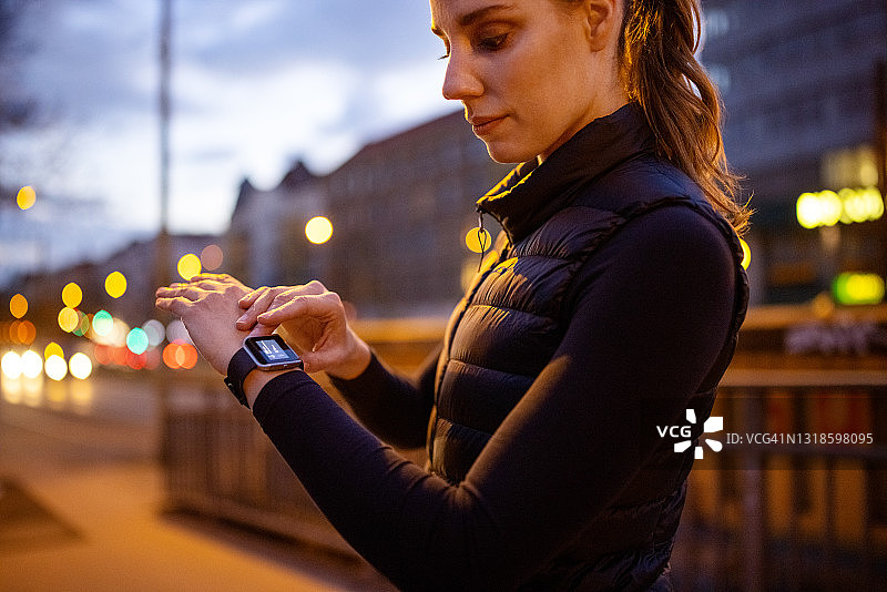 傍晚户外运动后查看智能手表的女人图片素材