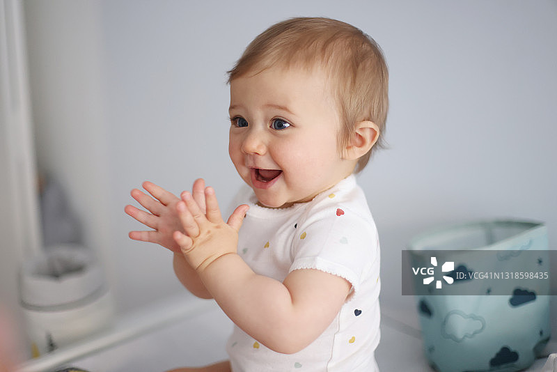 一个1岁大的女婴在换尿布台上拍手图片素材