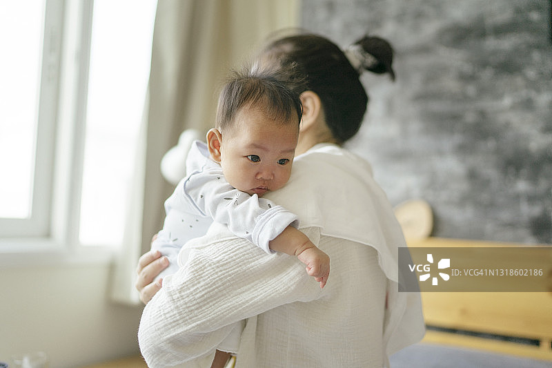单身母亲安慰在卧室里哭闹的新生女儿图片素材