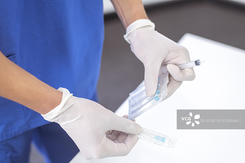 戴白色外科手套的护士从包装中取出针头图片素材