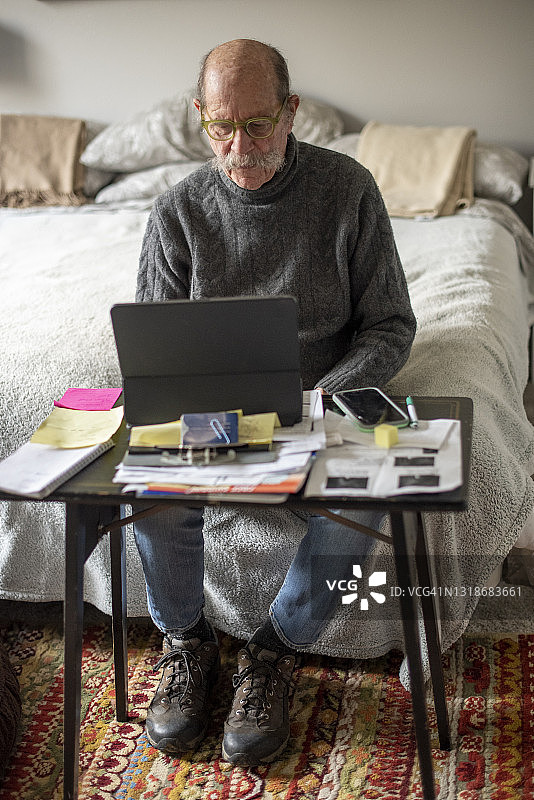 在卧室使用笔记本电脑的老年男人图片素材