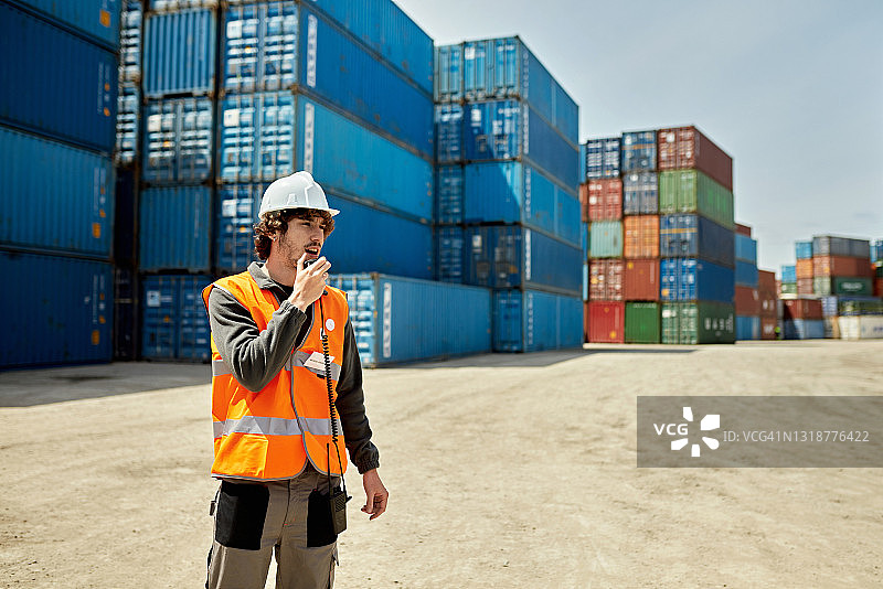在内陆港使用对讲机的白人男性货物搬运工图片素材