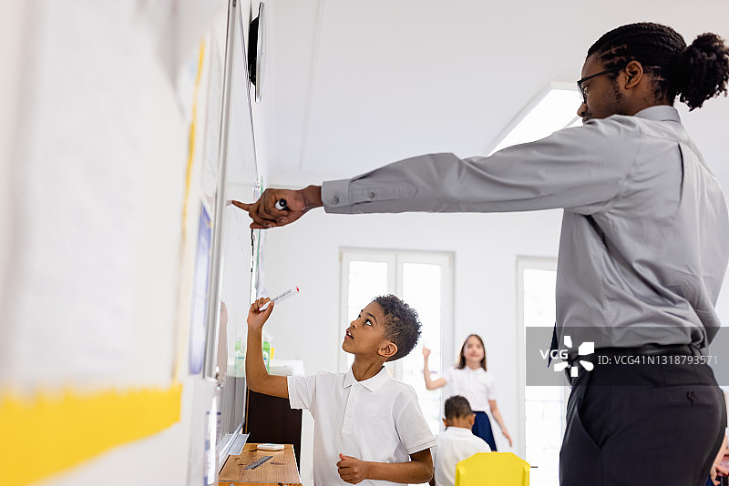 小学生在教室里站在白板旁回答问题图片素材