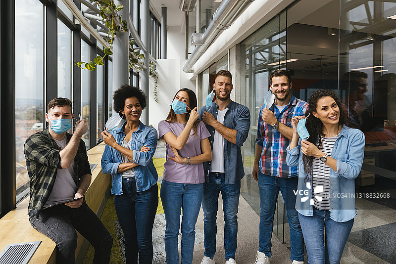 商务人士在办公室走廊站立时摘下防护口罩图片素材