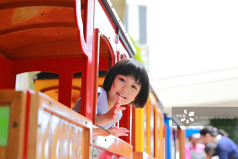 在购物中心乘坐巴士的混合种族小女孩看着镜头挥手告别图片素材
