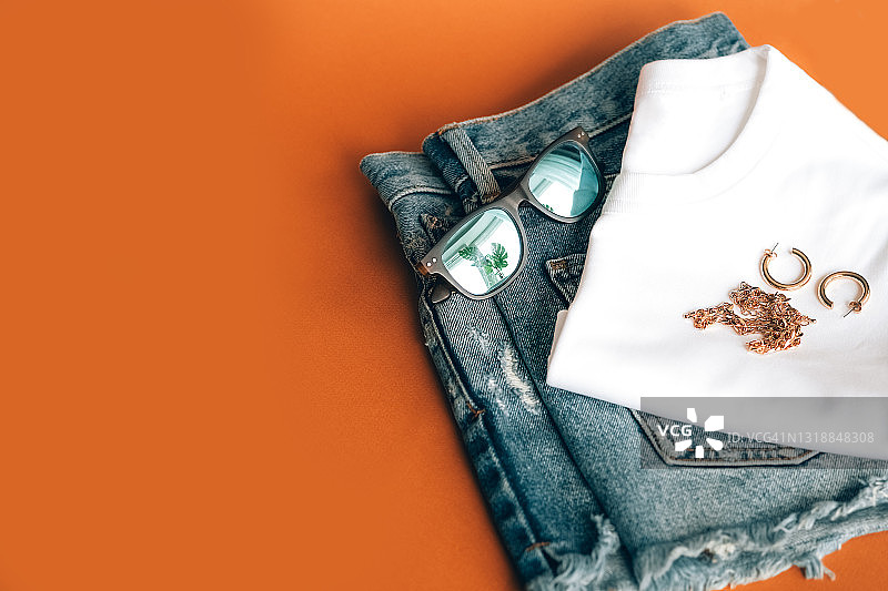 时尚女性夏季基础穿搭：太阳镜、牛仔短裤、白色T恤和配饰平铺图图片素材