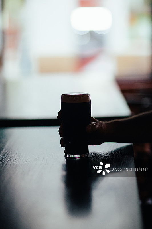 在酒吧里手拿一杯啤酒图片素材