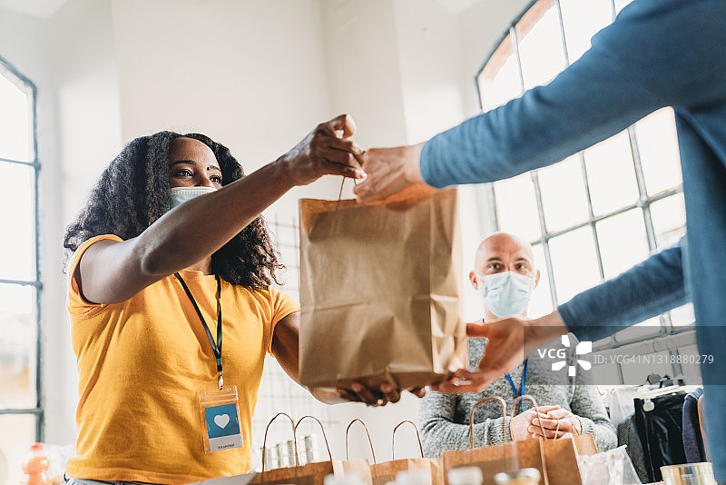 女人在食物和衣物银行取一份食物纸袋图片素材