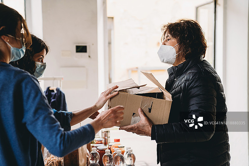 年长的女人在食物和衣物银行领取食物和饮料图片素材