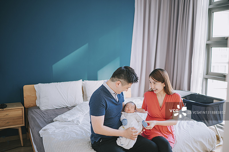 中国父母在卧室里充满爱意地抱着他们的新生男婴图片素材