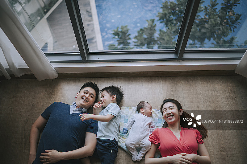 俯视：微笑的亚洲华人年轻家庭在地板上图片素材