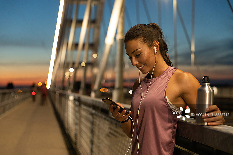 年轻女人训练后听音乐用手机图片素材