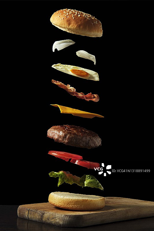 木板上黑色背景的飞行汉堡配料图片素材
