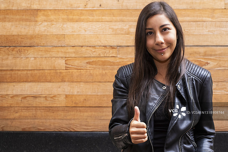 看着镜头并竖起大拇指的年轻拉丁裔女子图片素材