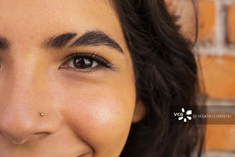 年轻拉丁裔女子面部特写，眉毛剃光图片素材