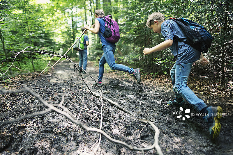 春季森林泥泞小路上徒步的家庭图片素材