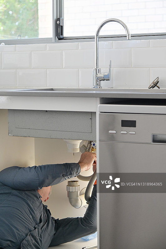 水管工正在修理和维修漏水的厨房水龙头图片素材