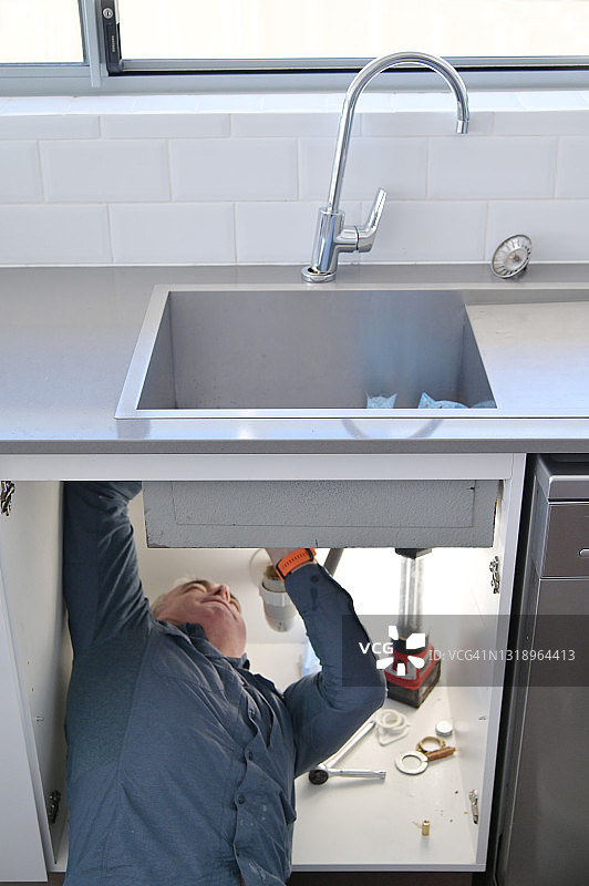 水管工正在修理和维修漏水的厨房水龙头图片素材
