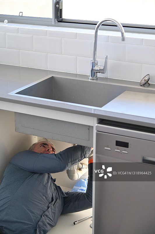 水管工正在修理和维修漏水的厨房水龙头图片素材