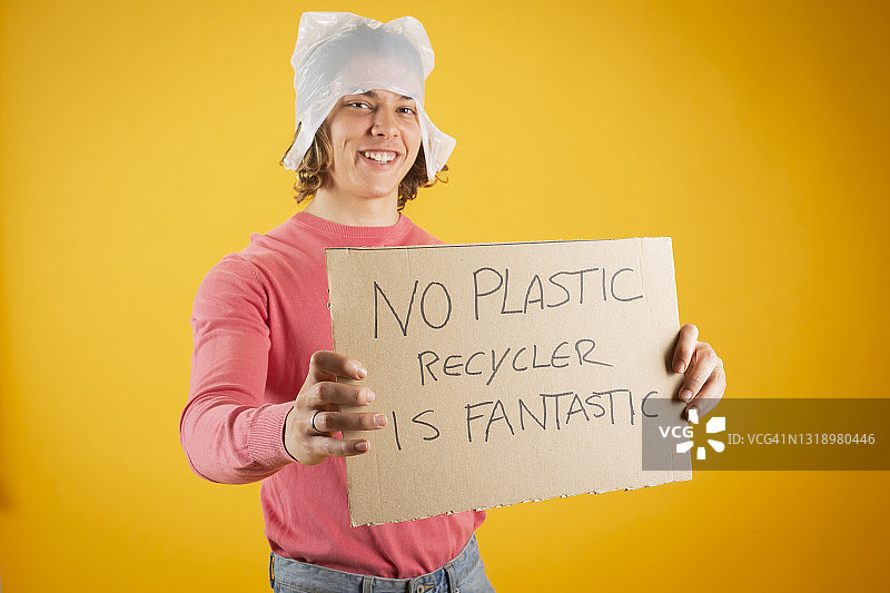 头上套着塑料袋，用手拿着回收标志的英俊金发男人图片素材