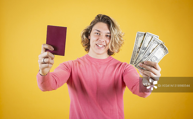 长发男人在黄色背景上手持护照和钱币图片素材