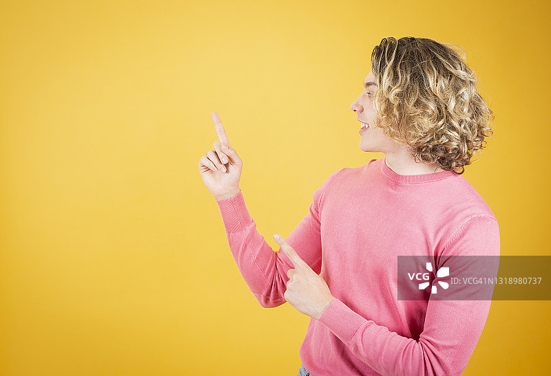 快乐的英俊长发男子指向黄色背景图片素材