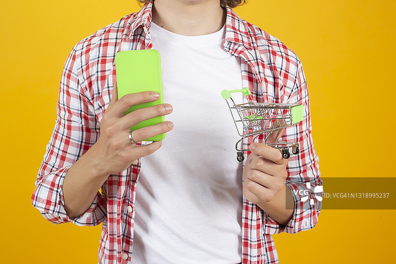 男人用手机和购物车在线购物图片素材