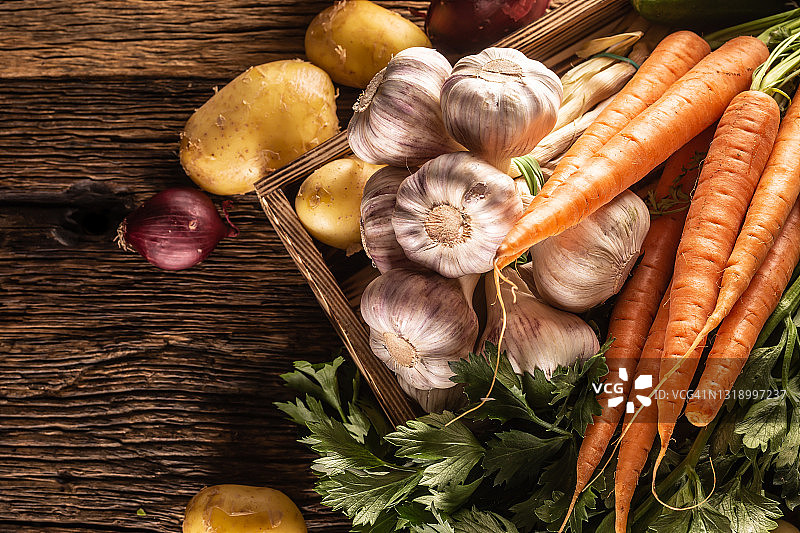 木桌上的自产蔬菜杂货俯视图：甜胡萝卜、土豆、黄瓜、洋葱和芳香蒜图片素材